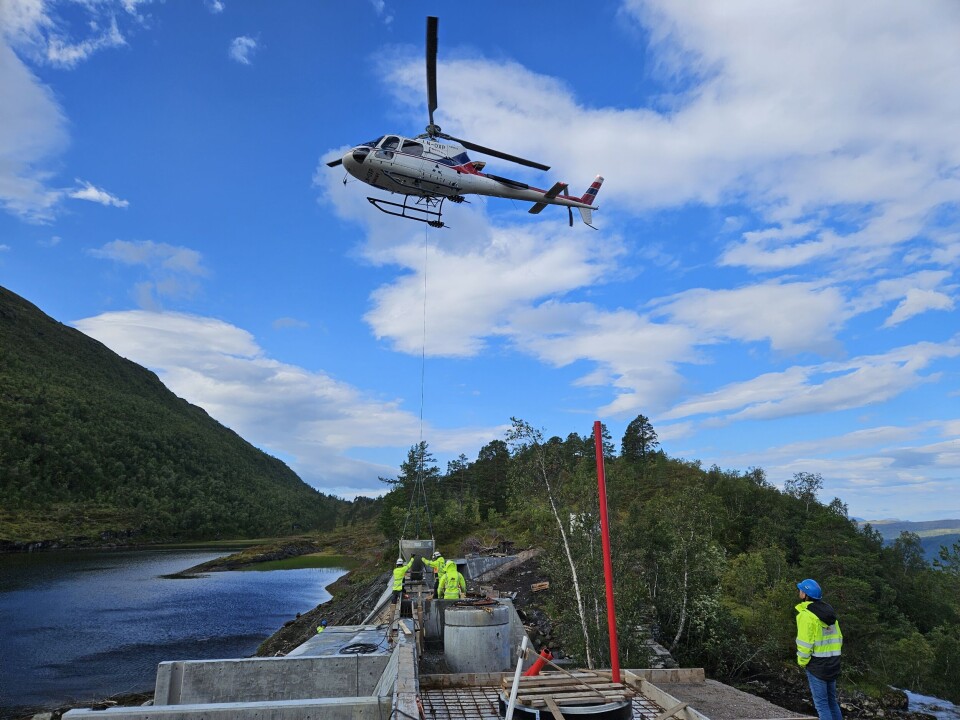 Her leveres betongen med stor presisjon fra helikopter til dammen ved Grytvatnet Helikopter leverer beting fra beholder hengende under