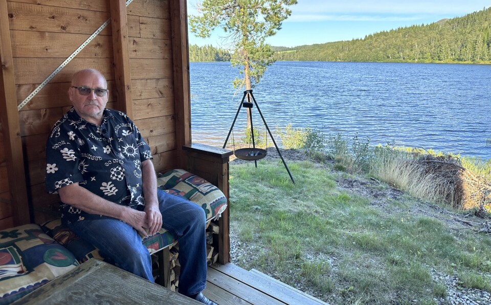 Arne Elshaug har bygd gapahuk ved Langvatnet i Rørdalen. En mann som sitter på en benk inne i en gapahuk ved et vann.