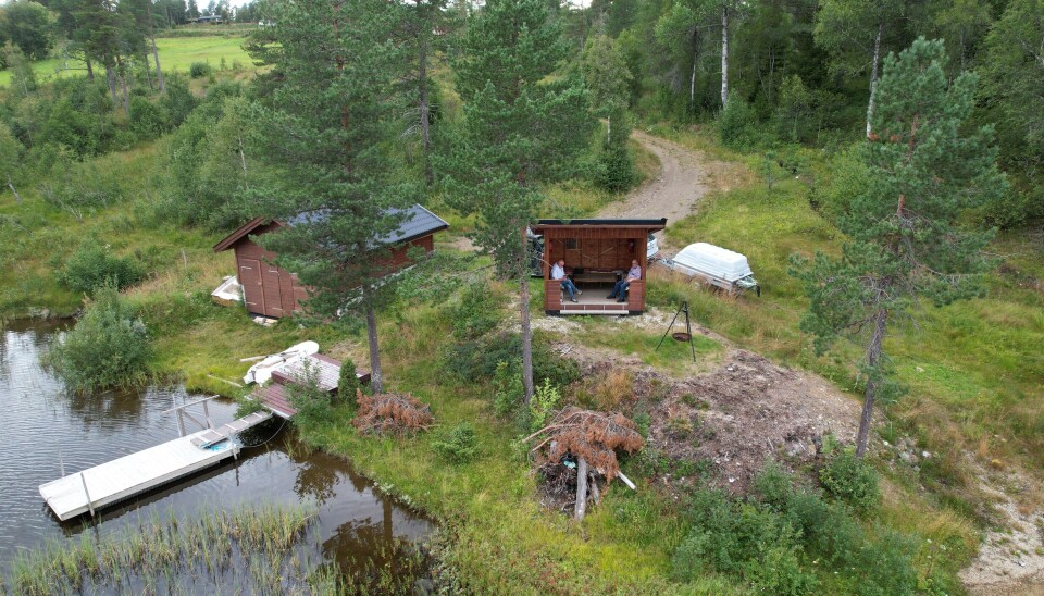 Gapahuken til Arne har hjul under, og kan snus etter sola. Den ligger nede ved Langvatnet, slik at flere kan bruke den. Dronebilde av et naust, ei brygge og en gapahuk ved et vann.