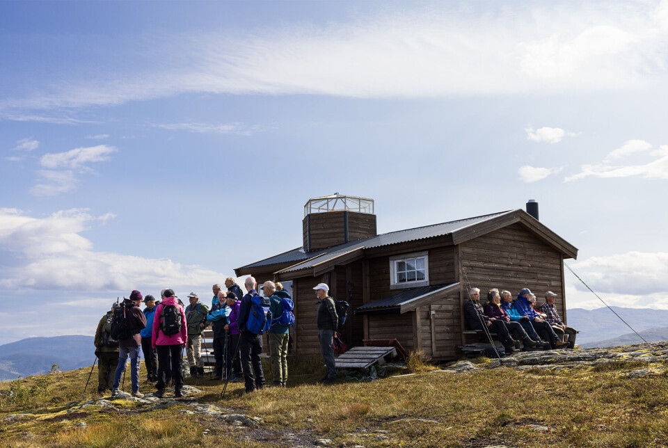 Hytta på Garbergsfjellet. Flere personer ved ei lita hytte på en fjelltopp.