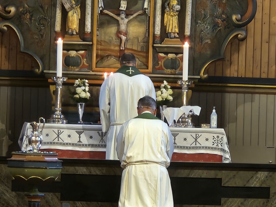 Prost Vidar W. Rygh foretek innsettingsseremonien som gjer Pål Arne Winsnes til sokneprest i Surnadal. prest og prost står med ryggen til i kirke