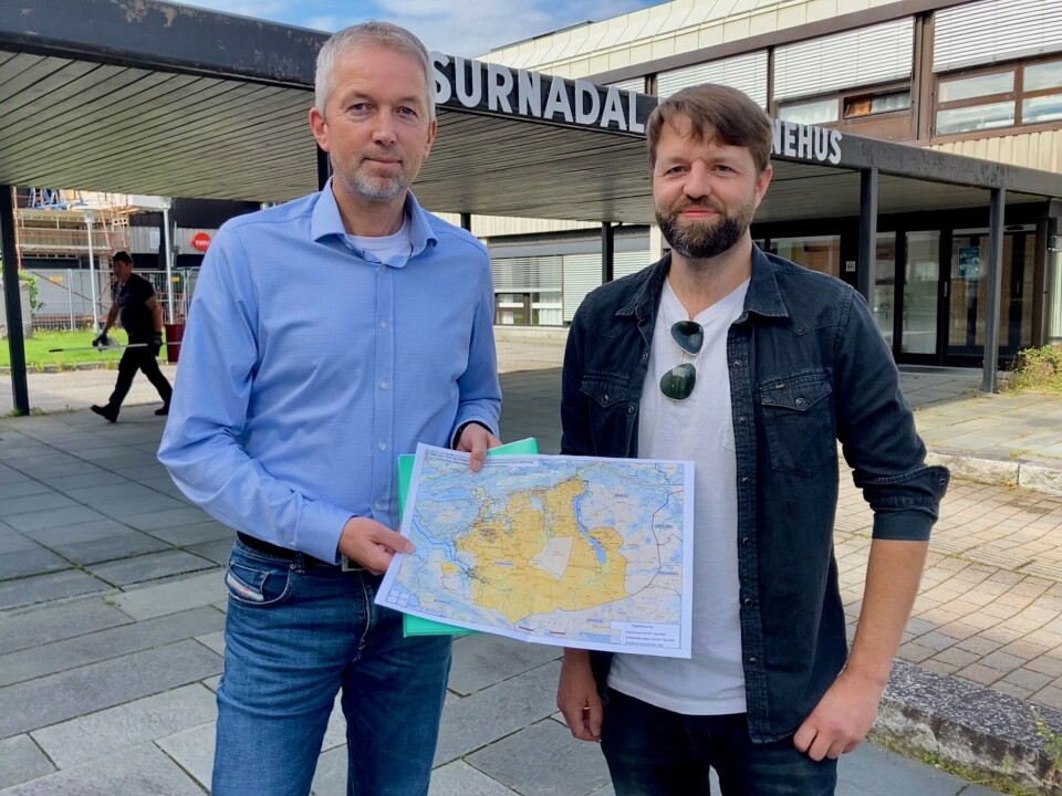Kommunedirektør Lars Inge Kvande tar i mot kart og brev med signaturer fra Eirik Fiske, på vegne av grunneiere i Trollheimen. To menn som holder frem et kart foran kommunehuset.