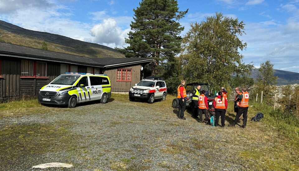 Letemannskap samlet ved Gråhaugen fjellstue fredag formiddag. Røde Kors-mannskaper i et fjellandskap. En politibil og en RødeKors-bil.