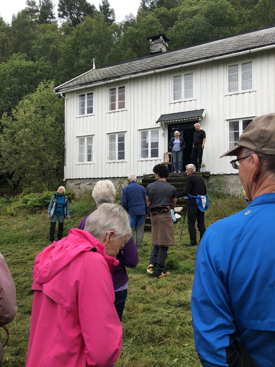 Øver-Trøinn på en tidligere Årnesdag. Gammelt hus med flere som venter foran huset.
