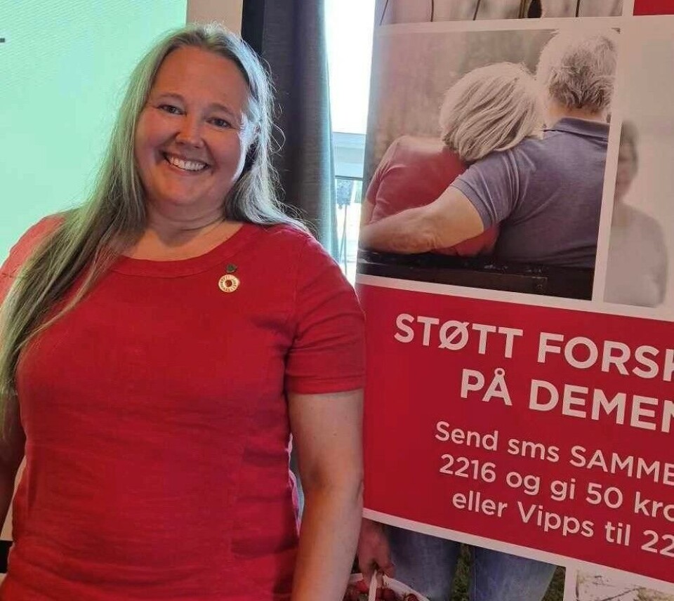 Annett Ranes. Ei smilende dame foran en plakat fra Nasjonalforeningen for folkehelsen.