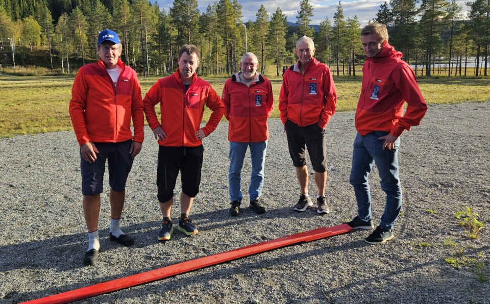 Rune Løfald er i teamet som er ansvarlig for målområdet. Her med en tredjedel av målstreken som skal nyttes under SKI- VM 2025. Fem menn i SKI VM jakker med en rød planke