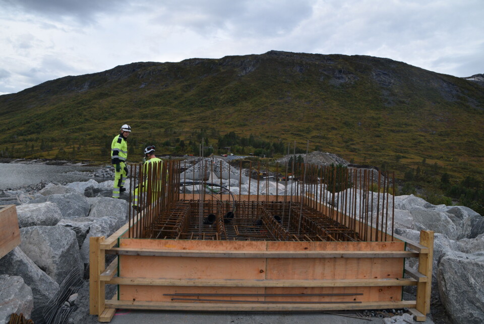 Her skal vannstanden i Gråsjømagasinet måles. To menn i varselklær oppe på toppen av en stor demning.