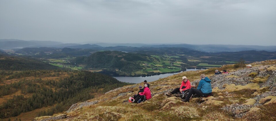 Tirsdagstur til Gimshøgda Tre turkledde personer som sitter på en fjelltopp og ser på utsikten.