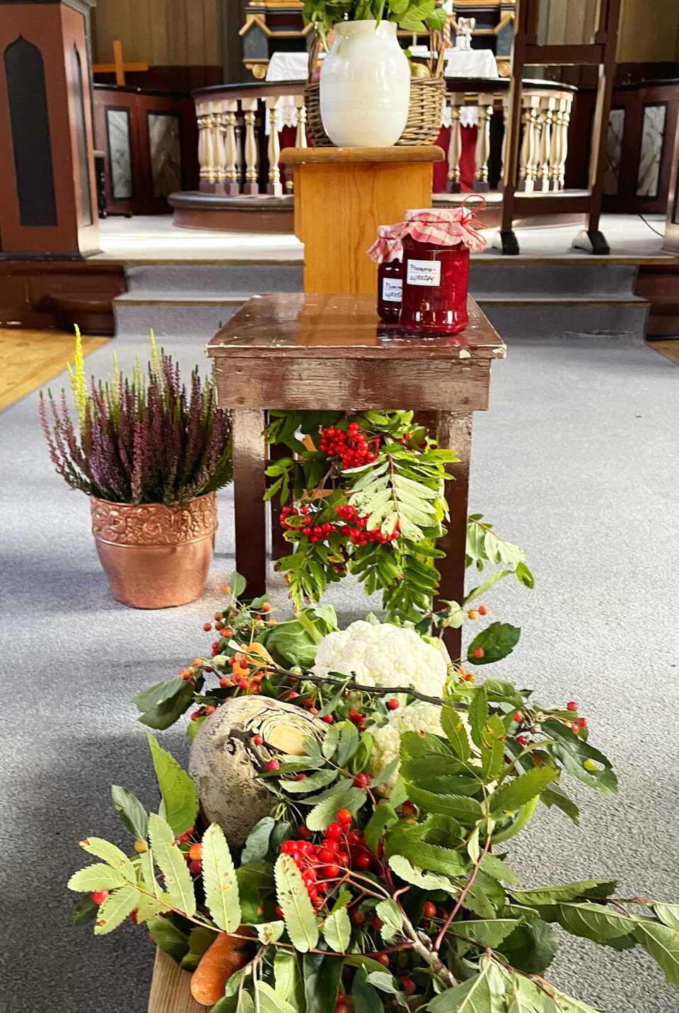 Tema: Takk! Rognbærkvister, grønnsaker, syltetøykrukker osv i midtgangen i ei kirke.