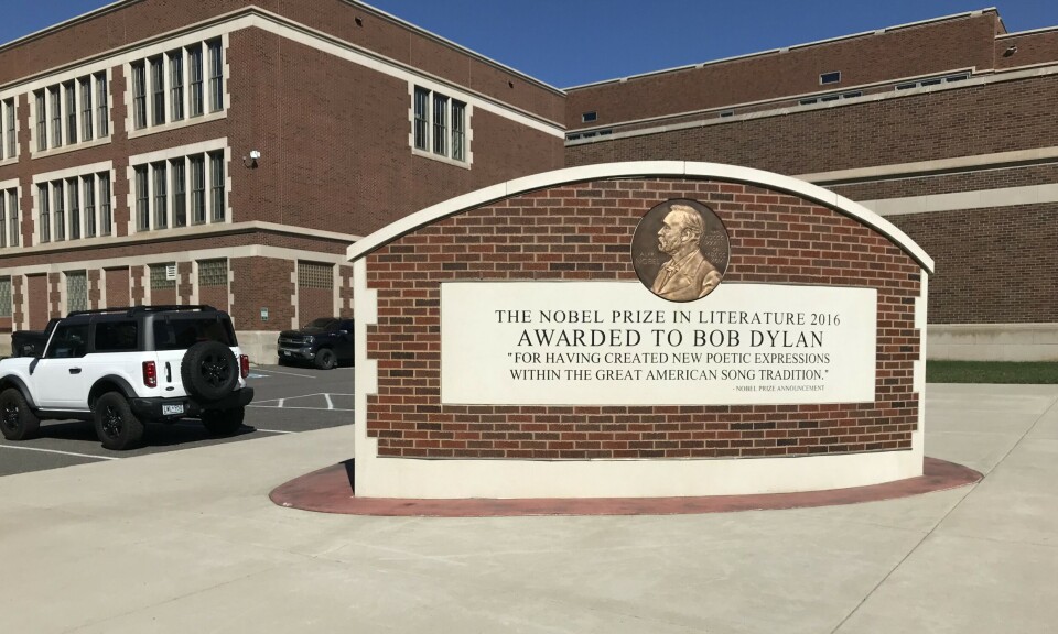 Hibbing High school, heder av Bob Dylan Et murbygg. Et monument for Bob Dylan foran.