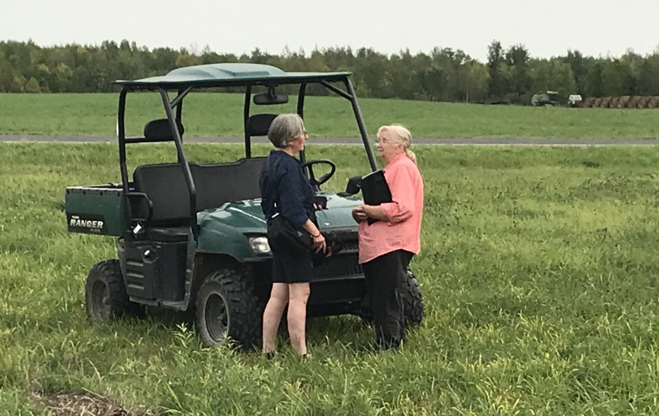 På farmen i Pinewood. To damer som står og snakker med hverandre ved siden av et terrengkjørtøy.
