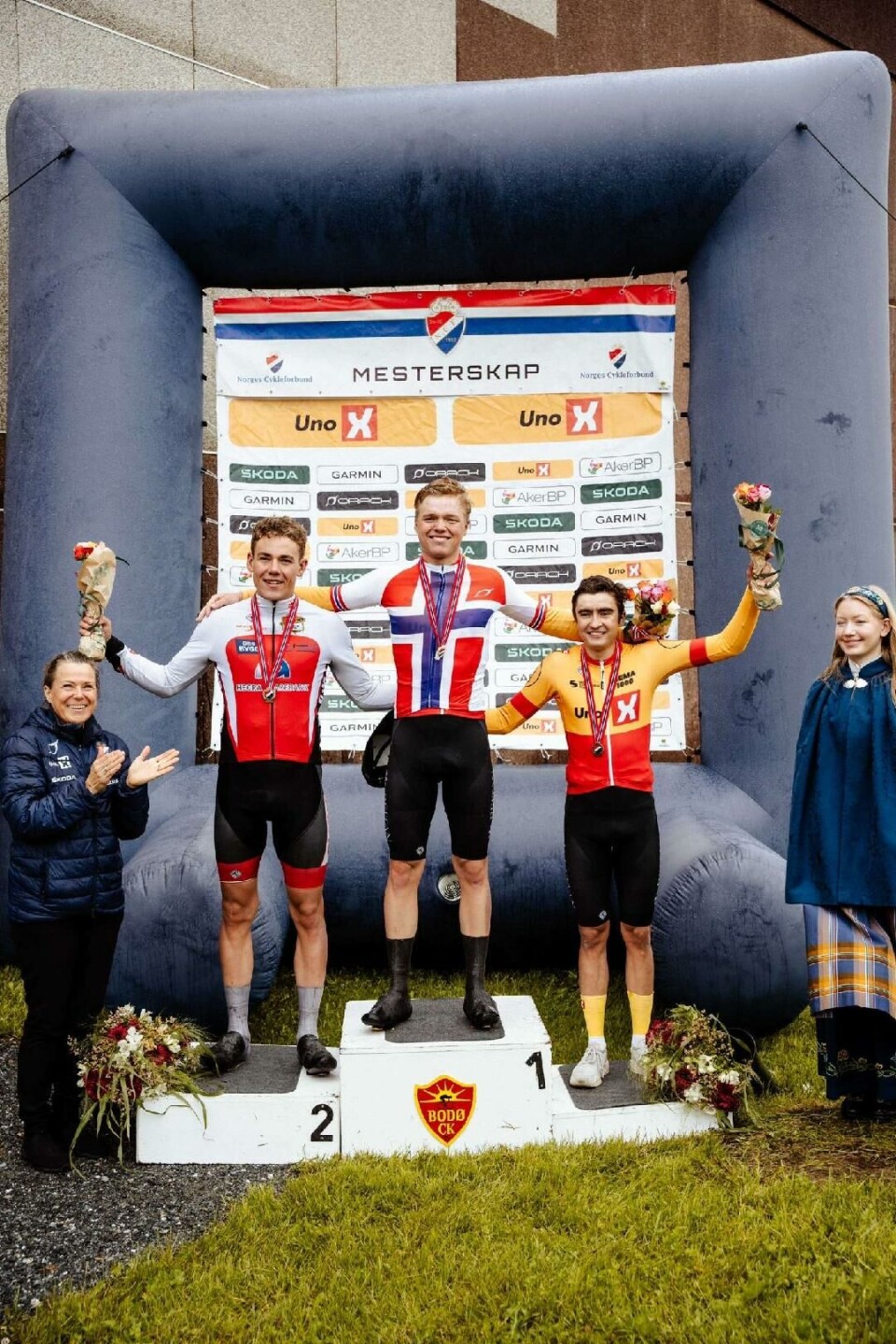 Tre ungdommer på en pall og en dame på hver side av de.