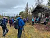 Flere turgåere foran ei gammel tømmerhytte i marka.