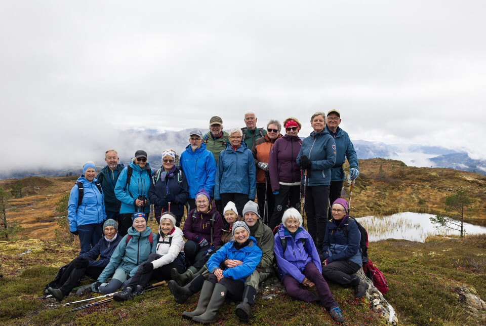 Alle 21, like blide. Ei gruppe med 21 turgåere, oppstilt for fotografering på en fjelltopp.