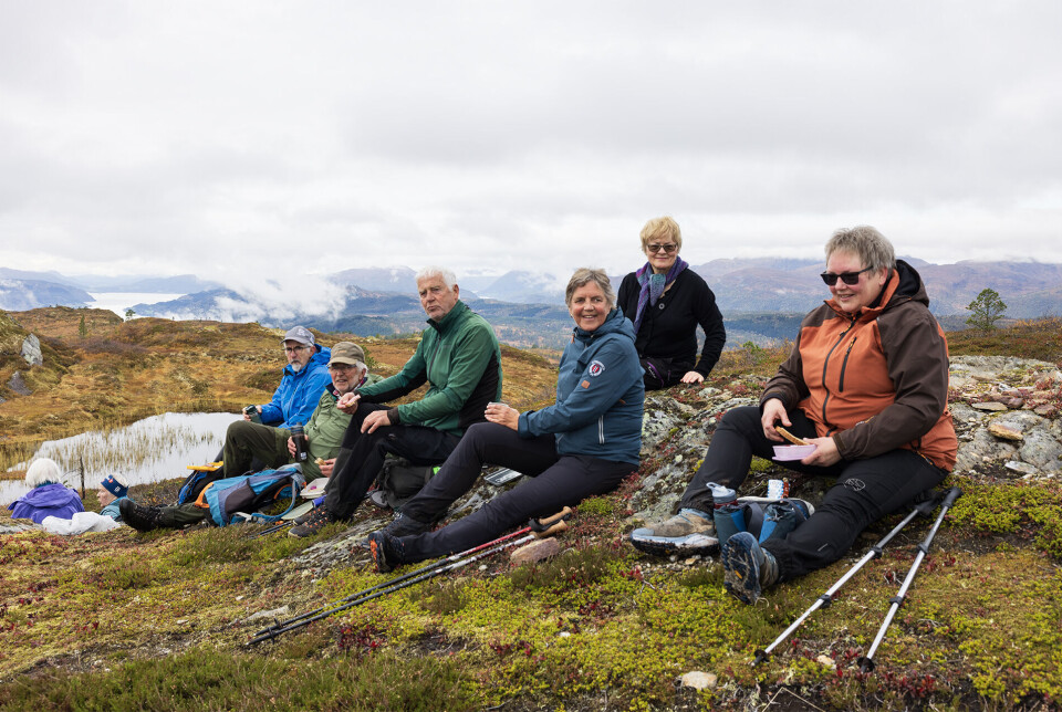 Herleg med kaffi og niste på toppen. Flere turkledde personer som har satt seg ned for en rast på fjellet.