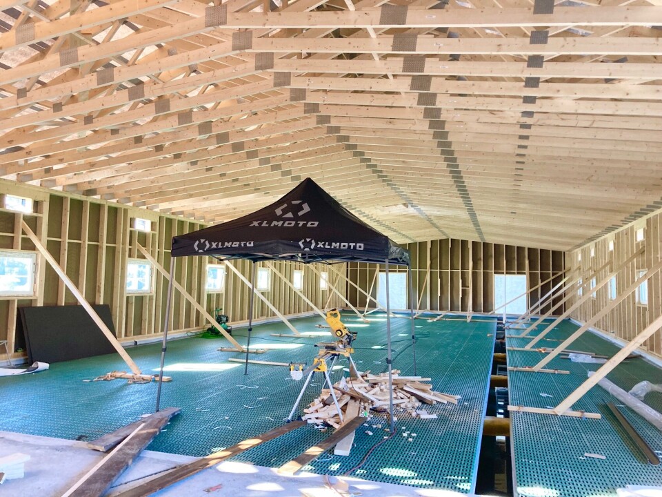 Det var var viktig for dem å benytte lokale håndverkere når de skulle sette opp det nye fjøset med trekonstruksjon. Fjøs under oppføring, med plastrister på gulvet og takelementer i tre.