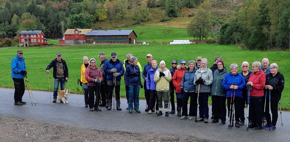 Stavgangtur til Øygardshalsen Ei gruppe turkledde pensjonister oppstilt for fotografering foran en gård.
