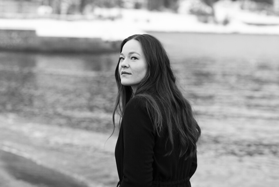 Dina Misund En mørkkledd dame med langt mørkt hår, utendørs foran et vann