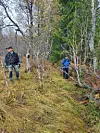 To menn står ved grøft i skogen