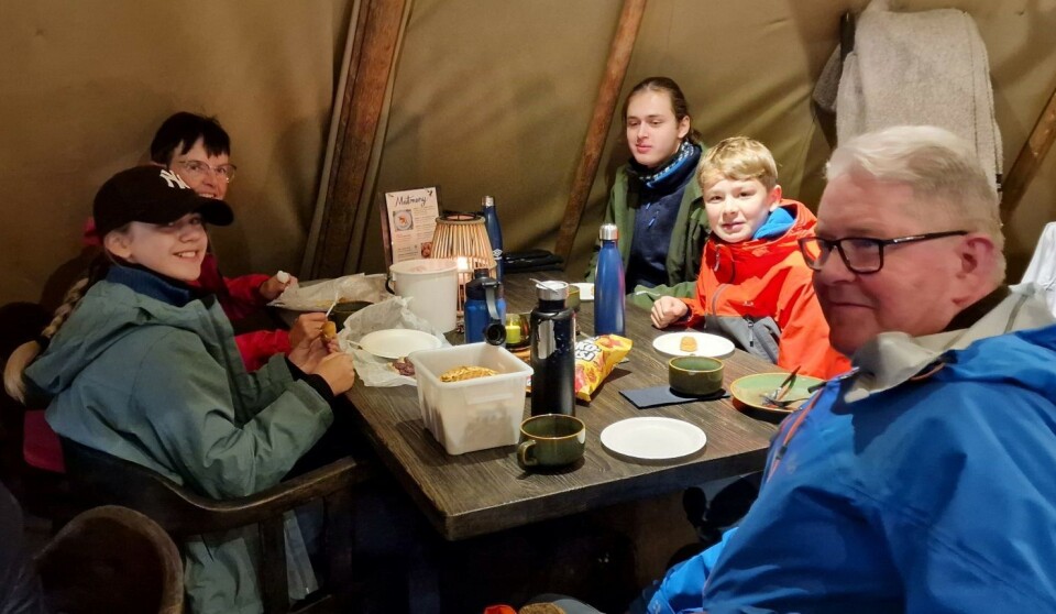 Maten smaker godt etter en gåtur først. Fem turkledde personer som spiser mat ved et bord inne i et stort telt.