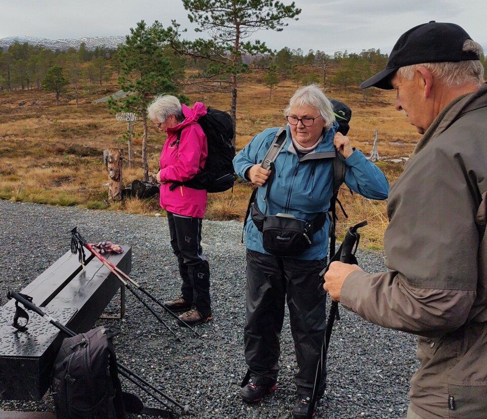 Tirsdagstur til Trollheimstunet -sesongavslutning En mann og to damer som tar på reyggsekk og gjør seg klare for å gå på en grussti i marka.