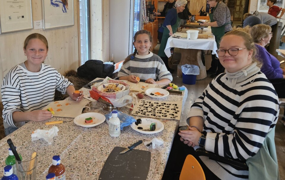 Ronja Solheim Romundstad, til venstre, og Helle Brauten lager potet-trykk på nett sammen med Anna Kristine Holm på Rindal Skimuseum To jenter og en dame sitter ved et bord med potet-trykk på nett