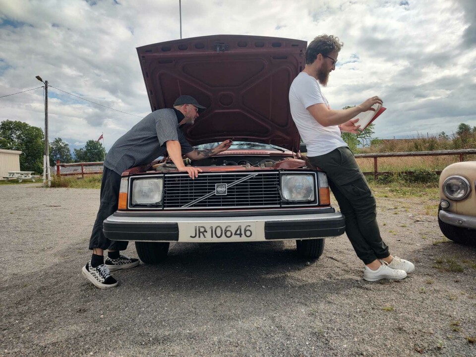 Bokprat med Anders Totland – med eller utan Volvo 245 To menn ved en Volvo med åpent panser. En leser i bok, den andre reparerer