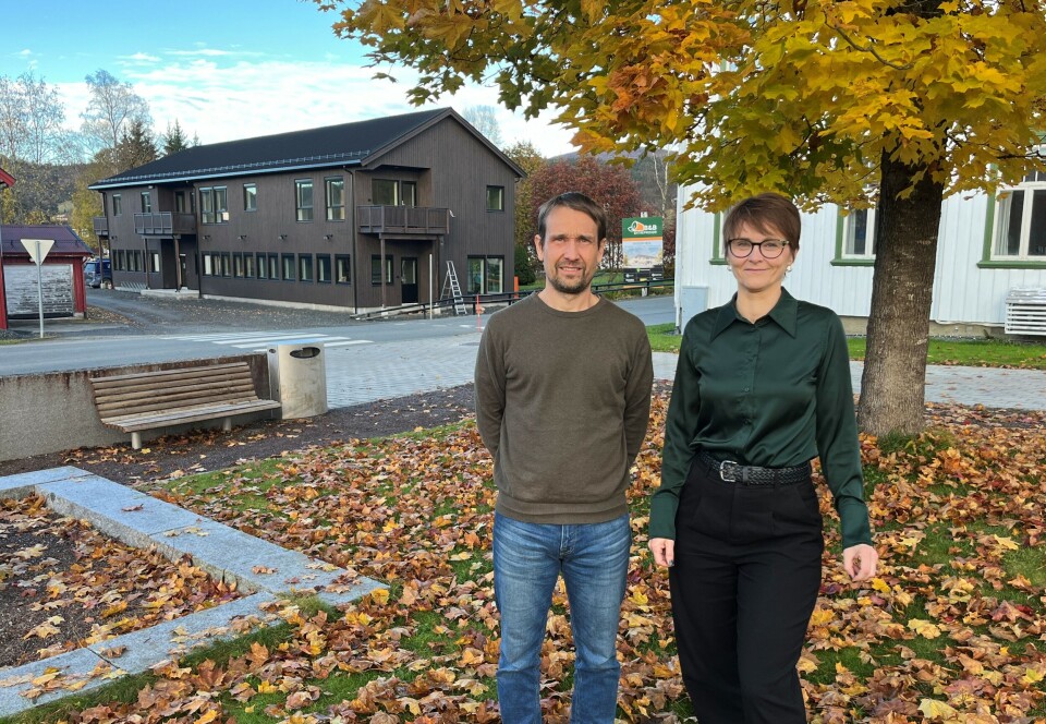 Økonomisjef Henning Andersen og ordfører Mildrid Kattem Aune, med det nye Hov-bygget i Rindal sentrum i bakgrunnen. En mann og ei dame i en park med høstløv.