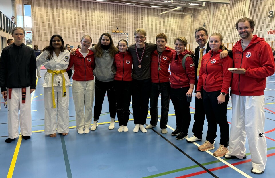 Gode resultater i Midt-Norsk mesterskap 11 taekwon-do-utøvere oppstilt for fotografering i en idrettshall.