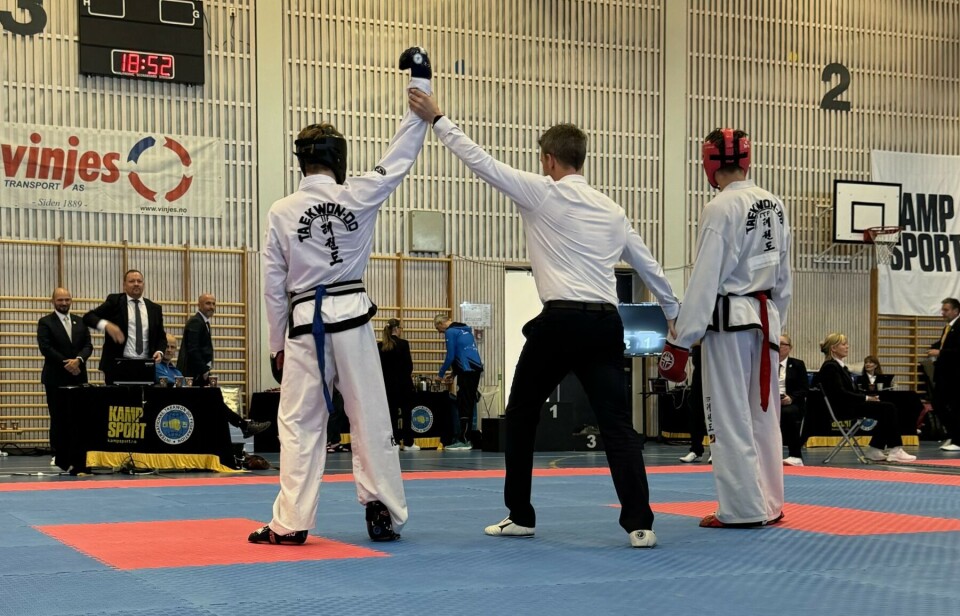 Gode resultater i Midt-Norsk mesterskap Taekwon-Do-utøvere på matta. Dommeren holder den ene utøverens hånd i været.