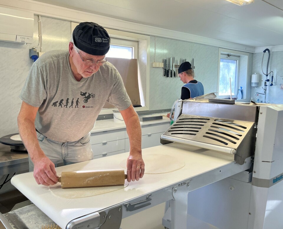 Lefsene trenger et par ekstra drag med kjevle for å bli tynne nok. En mann som står og kjevler ei stor tynn lefse på et produksjonsbånd i et bakeri.