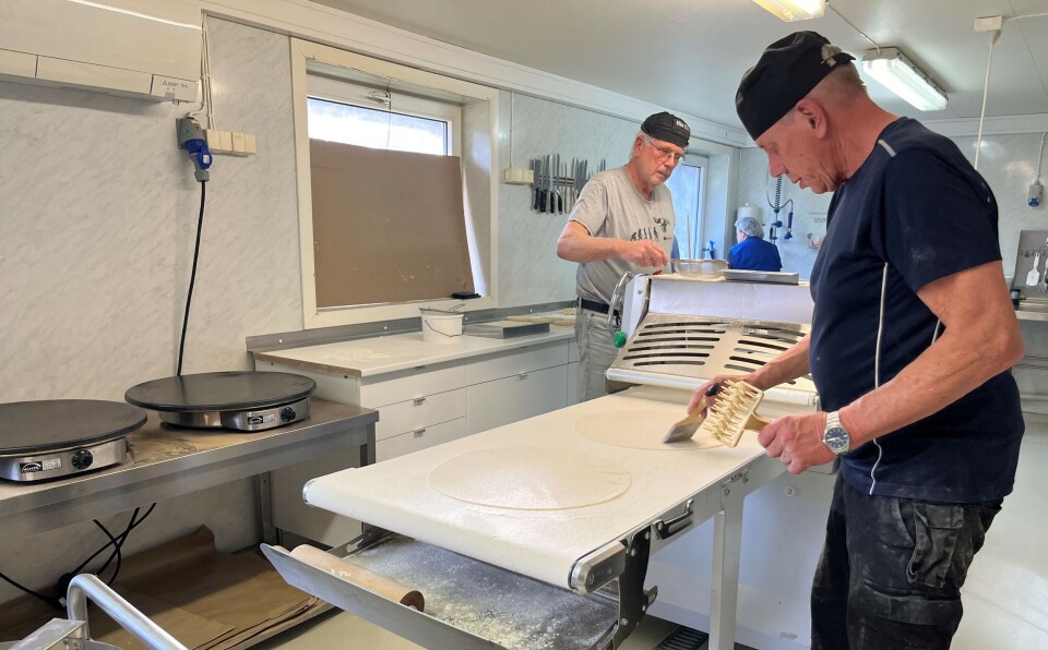 Overflødig mel kostes av. En mann som står med ei trinse og en kost over et produksjonbånd med tynnlefser i et bakeri.