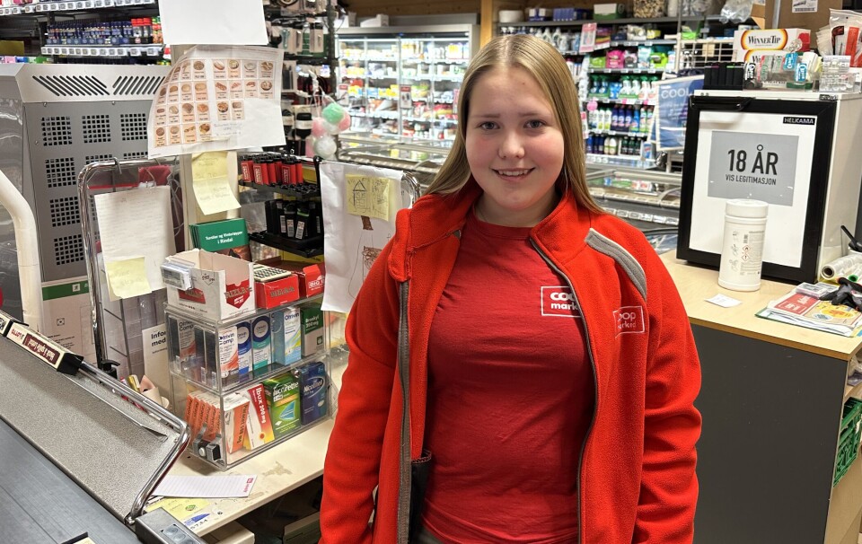 Ny assisterende butikksjef på Coop marked Nybø Ei ung dame som står bak kassen i en dagligvarebutikk.
