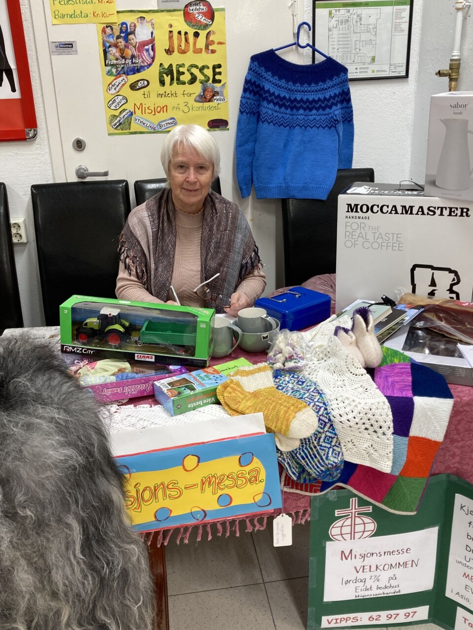 Anna Sæther selger lodd ved Coop på Skei. Her viser hun frem mange flotte gevinster. Dame ved bord med basarpremier