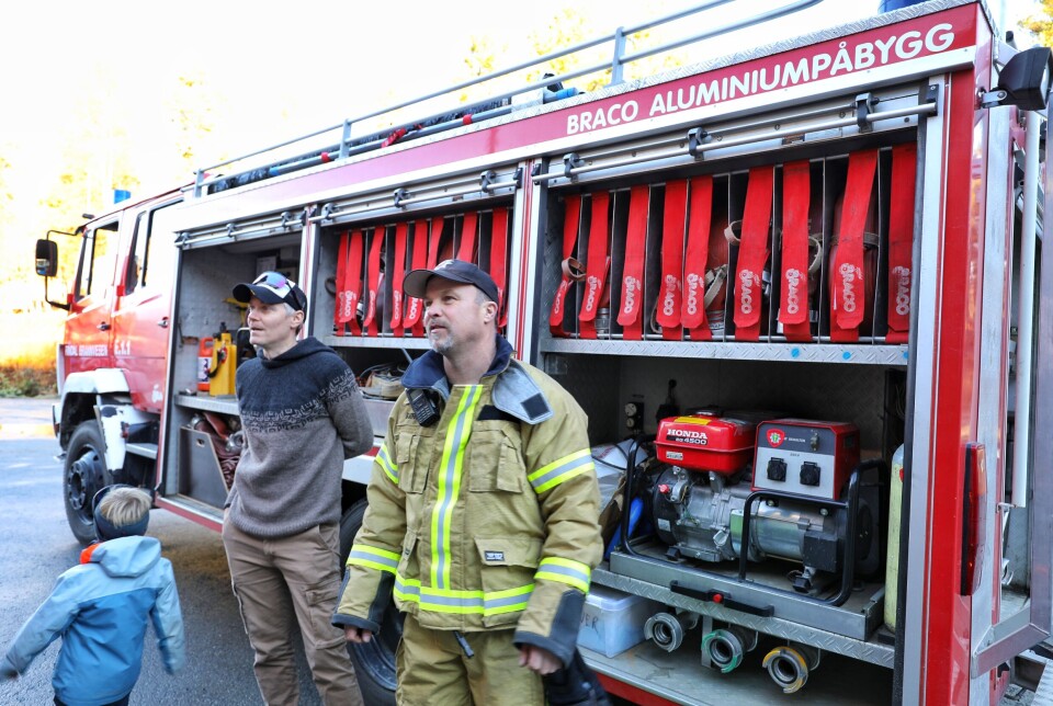 Den gamle brannbilen som har vært i tjeneste i 31 år. To menn står ved brannbilen som har alle sidelukene åpne for å vise frem utstyret.