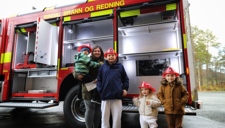Den nye brannbilen har plass til mer utstyr enn den gamle. Barn og voksne koste seg under åpen dag ved brannstasjonen. Alle som ville ha fikk brannhjelm. 4 barn med står foran nybilen som har åpne sideluker som foreløpig ikke er fylt opp. På hode har de brannhjelmer som de har fått i dag.