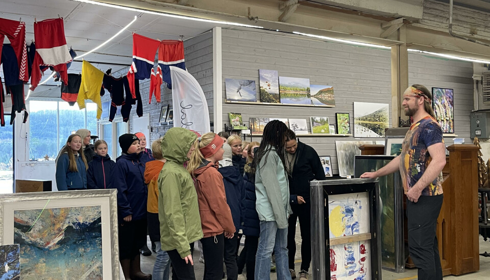 Aune Sand ønsker 6. klasse ved Rindal skole velkommen. En mann står foran en skoleklasse. Maleri