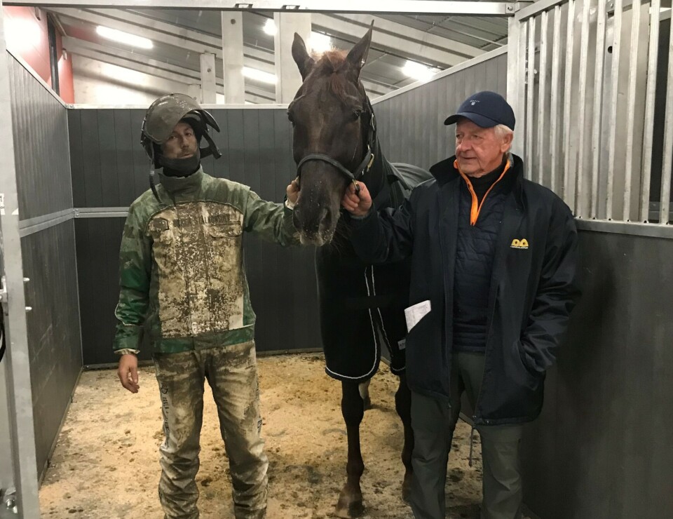 Mr. Pagadi med trener og kusk Inge Melby, og eier Ola Sylte Heggset. En travkusk med mye søle på drakten og en annen mann står sammen med en hest i en oppselingsboks.