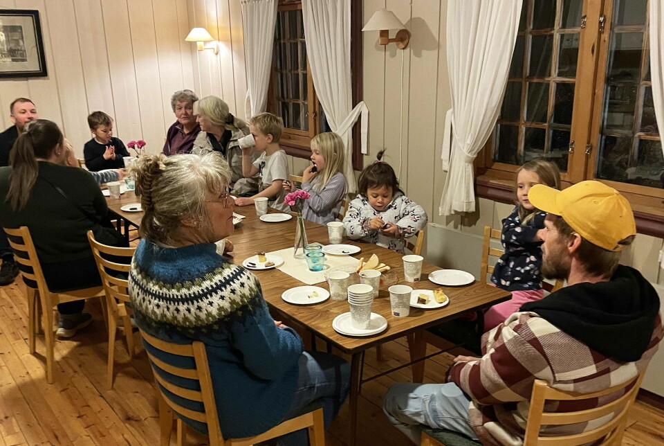 Det smaka godt med mat og frukt etterpå. Flere barn og voksne som sitter rundt et stort langbord med mat.