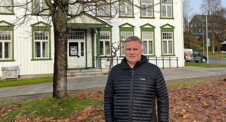 Kåre Herrem er ansvarlig for oppvekst, beredskap og informasjon i Rindal kommune. En mann foran en stor gammel trebygning.