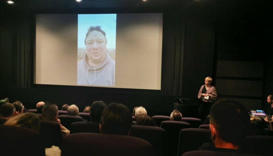 Tor Jacob Solberg med videohilsen på storskjerm under årets landbrukskonferanse i Surnadal. Mann avbildet på storskjerm i konferansesal.