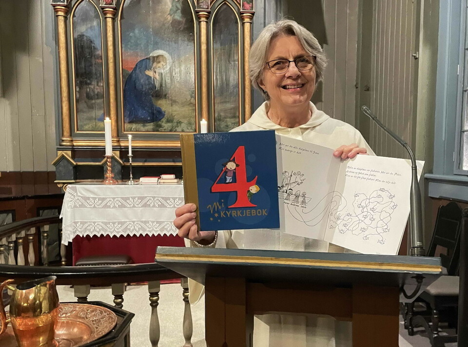 Klokkar Randi Bøe gled seg til å dele ut «Mi Kyrkjebok» til 4-åringane og håpar mange, små og store, blir med på gudstenesta. Ei dame på prekestolen i ei kirke, med to bøker foran seg.