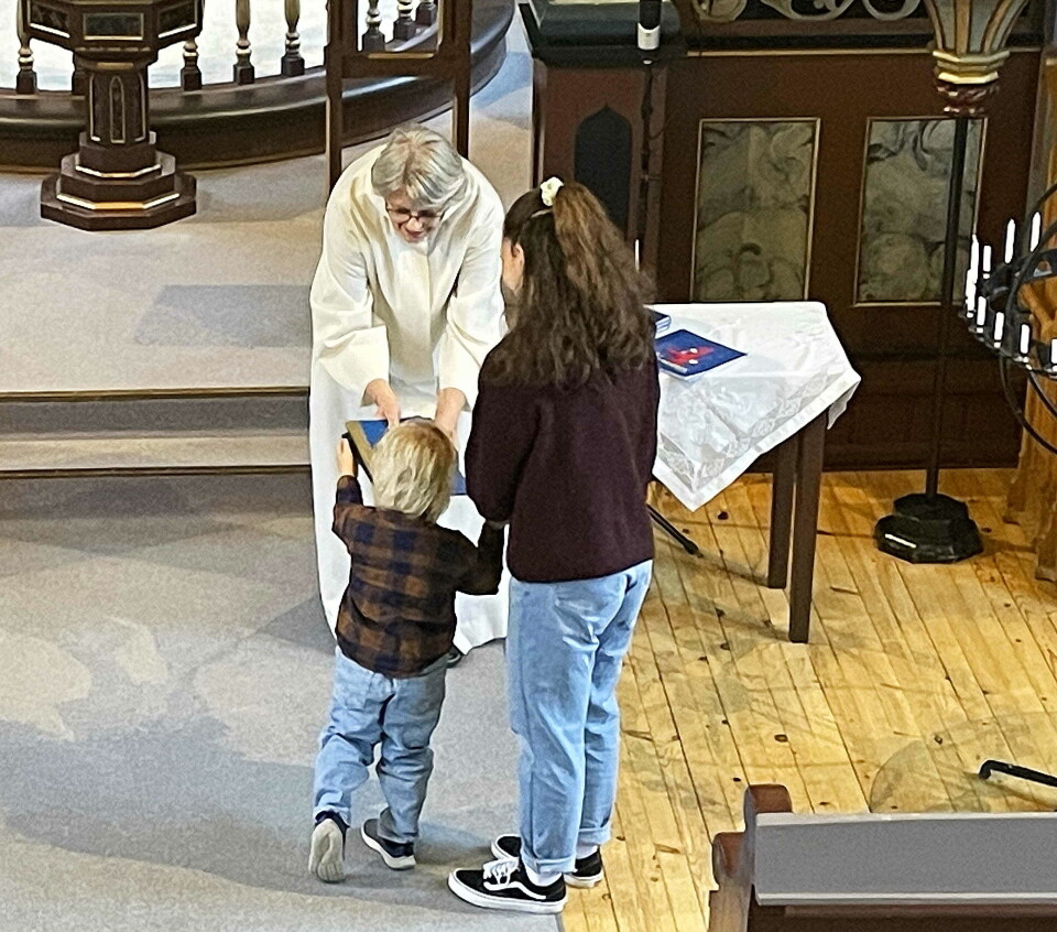 Ein av dei spente 4-åringane får kyrkjeboka si.