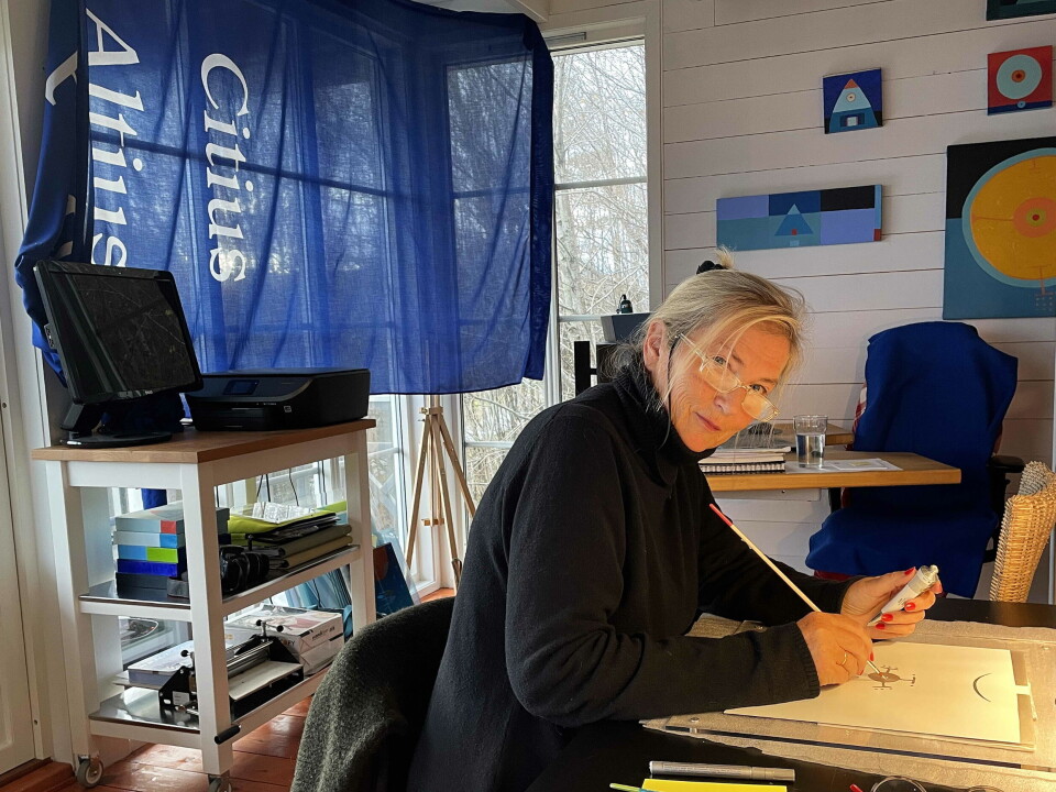 Ved arbeidsbordet – og med minne frå Lillehammer-OL vaiande ved glaset.