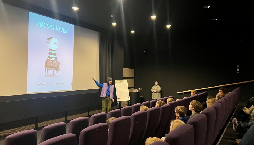 Engedal leste høgt frå boka si 'Pølsetjuven' og elevane fekk vere med å seie kva dei trudde skulle skje i boka. forfatter peker på bilde av bok i kinosal