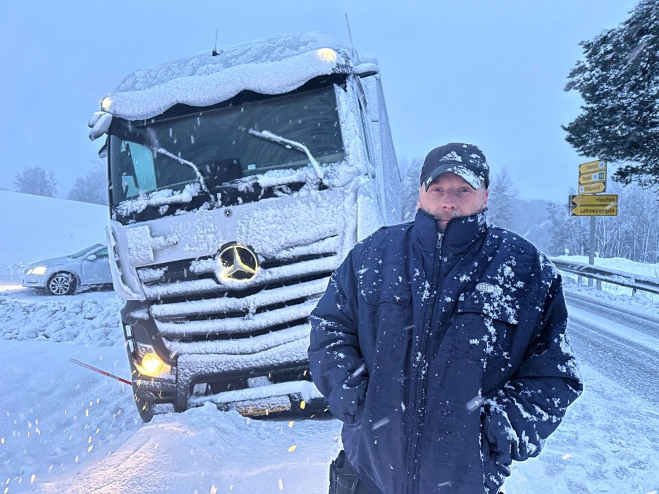 Utfordrende føre skaper problemer En mann som står foran et vogntog som har kjørt av veien i snøvær.
