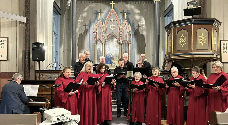 Prosjekt 17 «varma opp» til komande søndags julekonsertar – her i finalesalmen «Jeg tror på jordens forvandling». Et kor, flere personer i korkapper, som står og synger i koret i ei kirke.