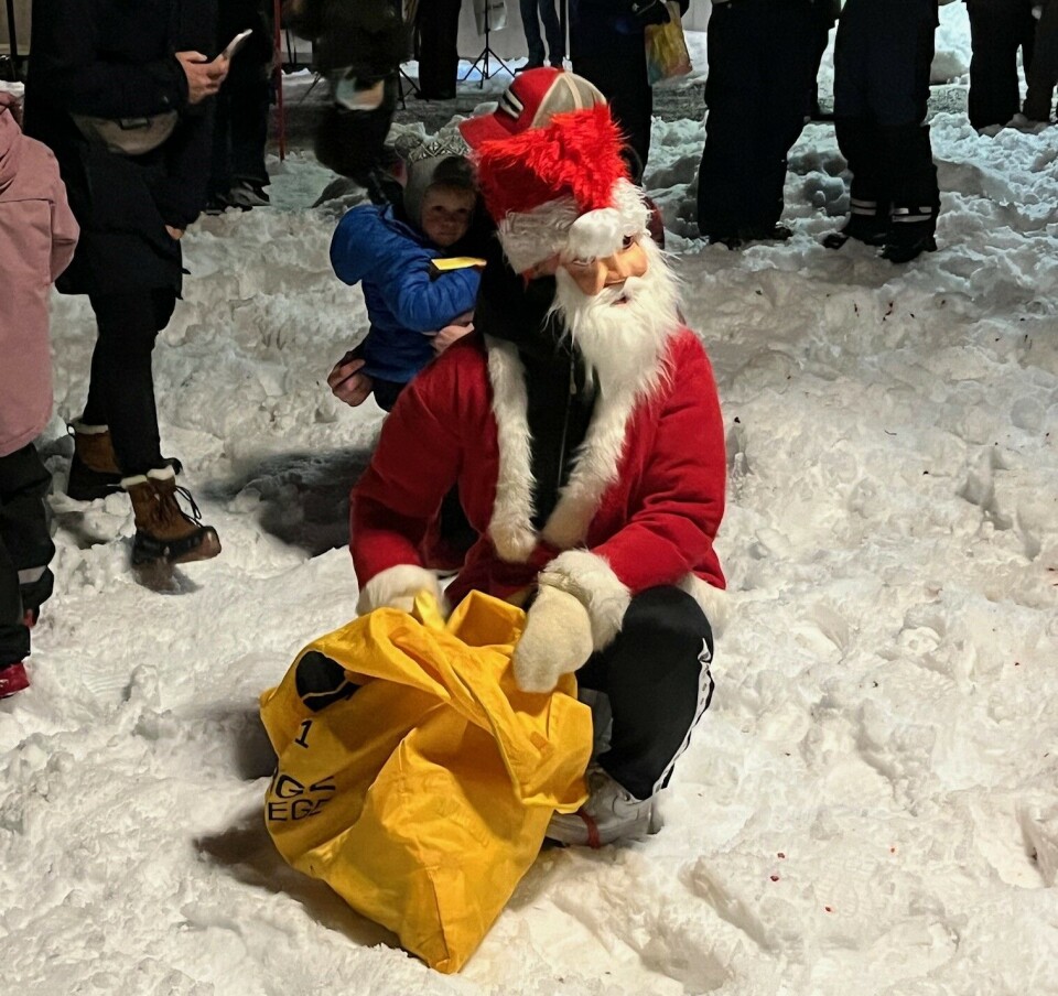 Trivelig julegrantenning på Rindalstorget En julenisse som sitter i snøen med sekken sin.