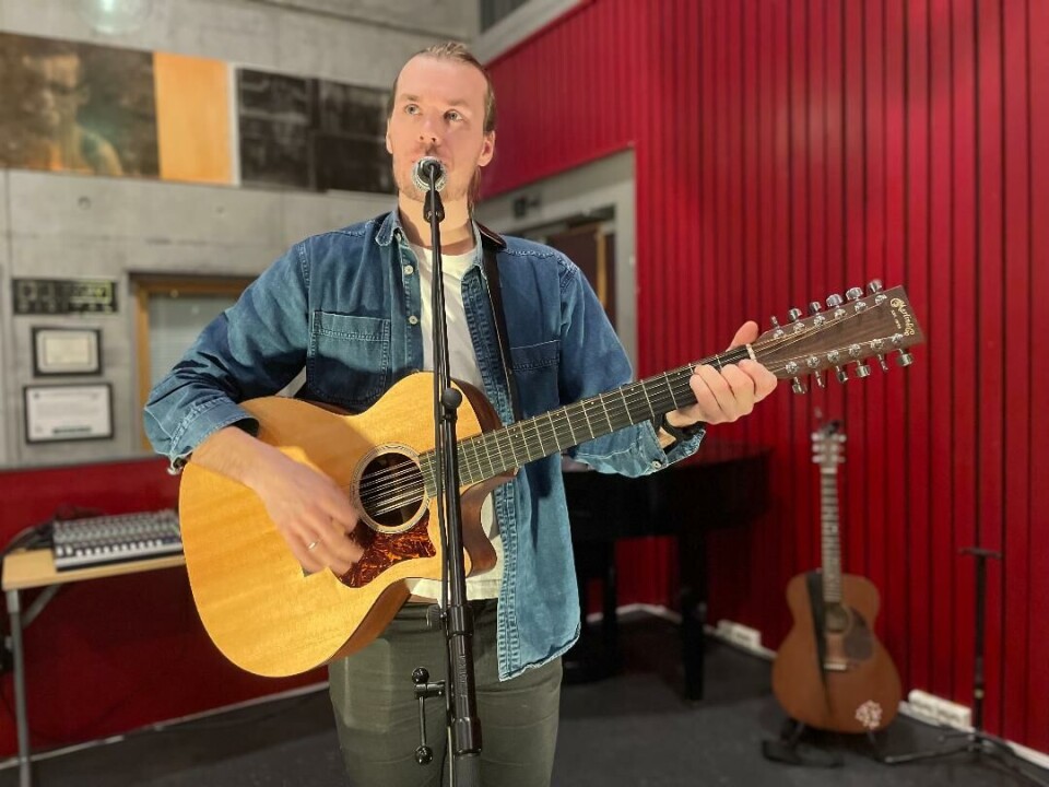 Jo Sverre på Surnadal kulturhus lørdag kveld. Mann spiller på gitar og synger i mikrofon.