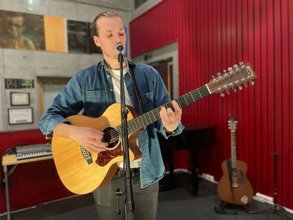Ostoppele - både i foajéen og i grunnskolepensum Mann spiller på gitar og synger i mikrofon.
